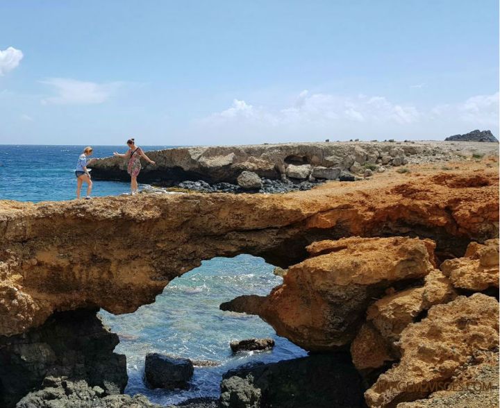 Foto de uma ponte formada por rochas em Aruba, acima do mar
